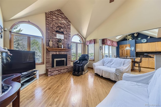 7043 S Owens Way, Littleton, CO 80127 - living area with light wood-style flooring, a brick fireplace, ceiling fan, and high vaulted ceiling
