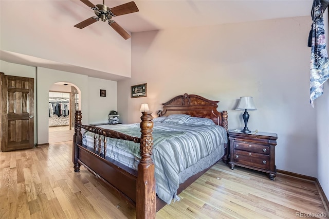 7043 S Owens Way, Littleton, CO 80127 - bedroom featuring arched walkways, light wood-style flooring, a spacious closet, ceiling fan, and high vaulted ceiling