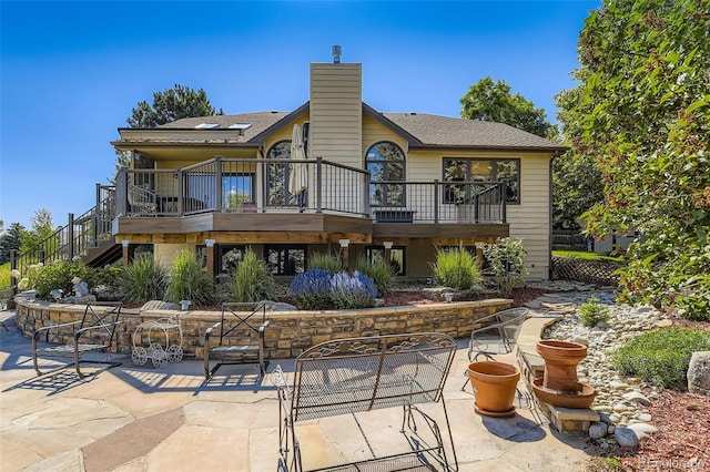 7043 S Owens Way, Littleton, CO 80127 - back of property featuring a patio, stairs, a wooden deck, and a chimney