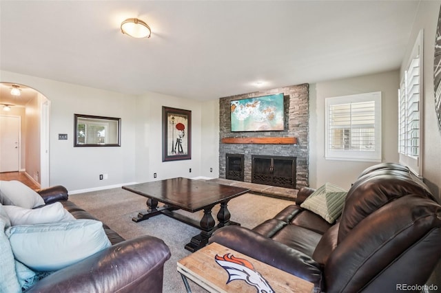 7311 Rattlesnake Dr, Lone Tree, CO 80124 - living room with arched walkways, a stone fireplace, and carpet flooring