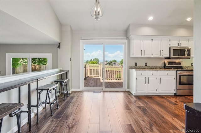 7311 Rattlesnake Dr, Lone Tree, CO 80124 - kitchen with appliances with stainless steel finishes, white cabinets, dark wood-style floors, recessed lighting, and dark stone countertops