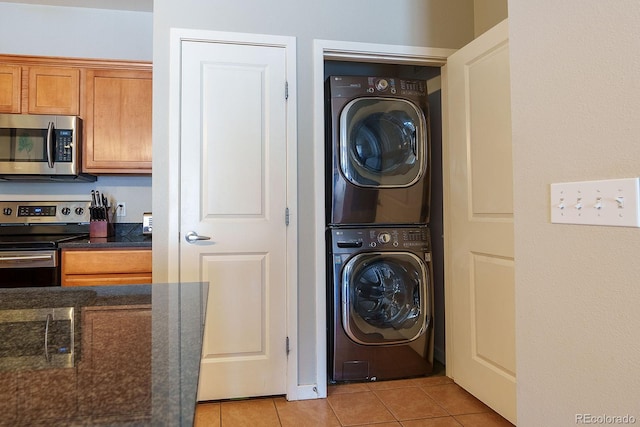 laundry room featuring stacked washer / dryer and light tile patterned flooring