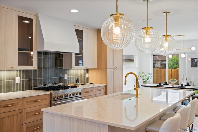 1645 N Osceola St, Denver, CO 80204 - kitchen with stainless steel stove, premium range hood, an island with sink, decorative backsplash, and light stone countertops