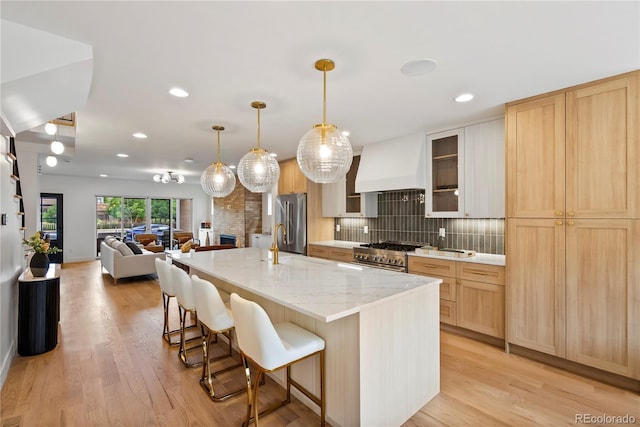 1645 N Osceola St, Denver, CO 80204 - kitchen with custom exhaust hood, stainless steel appliances, light brown cabinets, a breakfast bar, and tasteful backsplash