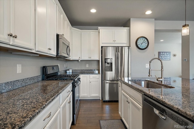 kitchen featuring appliances with stainless steel finishes, white cabinetry, dark stone countertops, and sink