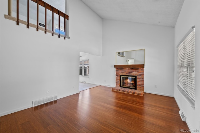 unfurnished living room featuring visible vents, plenty of natural light, wood finished floors, and high vaulted ceiling