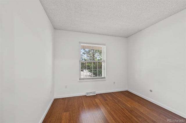 unfurnished room with visible vents, baseboards, a textured ceiling, and wood finished floors