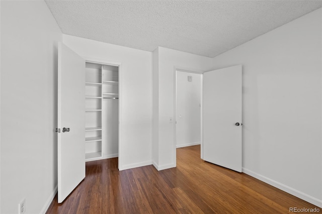 unfurnished bedroom featuring a closet, a textured ceiling, dark wood finished floors, and baseboards