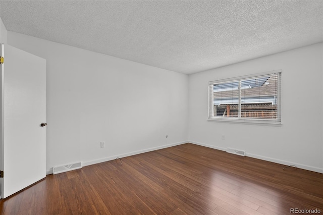 spare room featuring visible vents, a textured ceiling, and wood finished floors