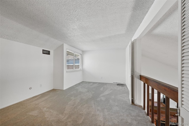 spare room featuring carpet flooring, a textured ceiling, and visible vents