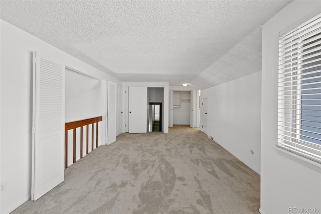 carpeted spare room with a textured ceiling and vaulted ceiling