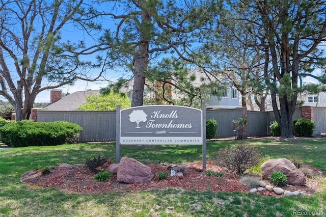 community / neighborhood sign featuring a lawn and fence