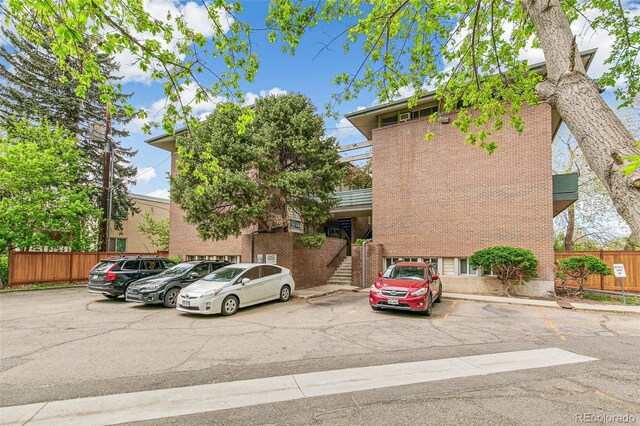 view of property featuring uncovered parking, fence, and stairway