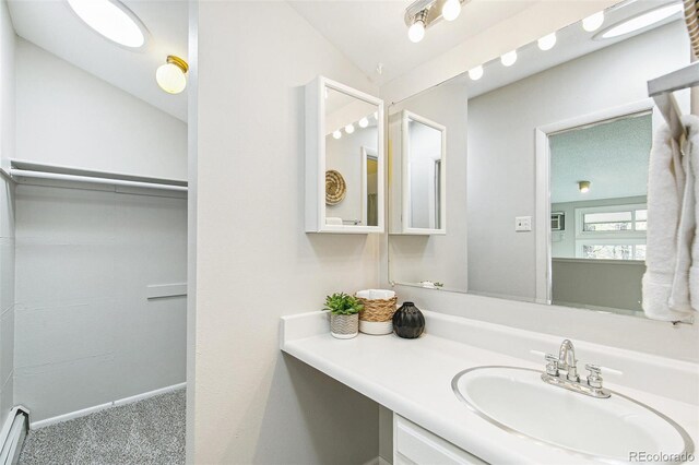 bathroom with baseboards, lofted ceiling, and vanity