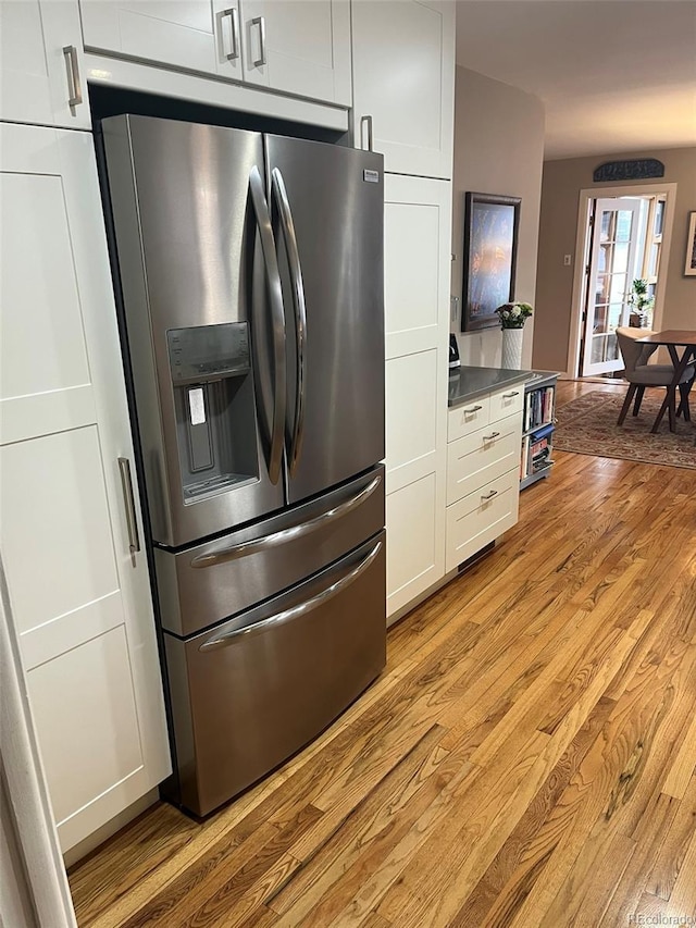 kitchen with white cabinets, light wood-type flooring, and stainless steel fridge