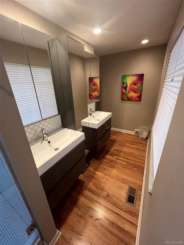 bathroom featuring hardwood / wood-style flooring, decorative backsplash, and vanity