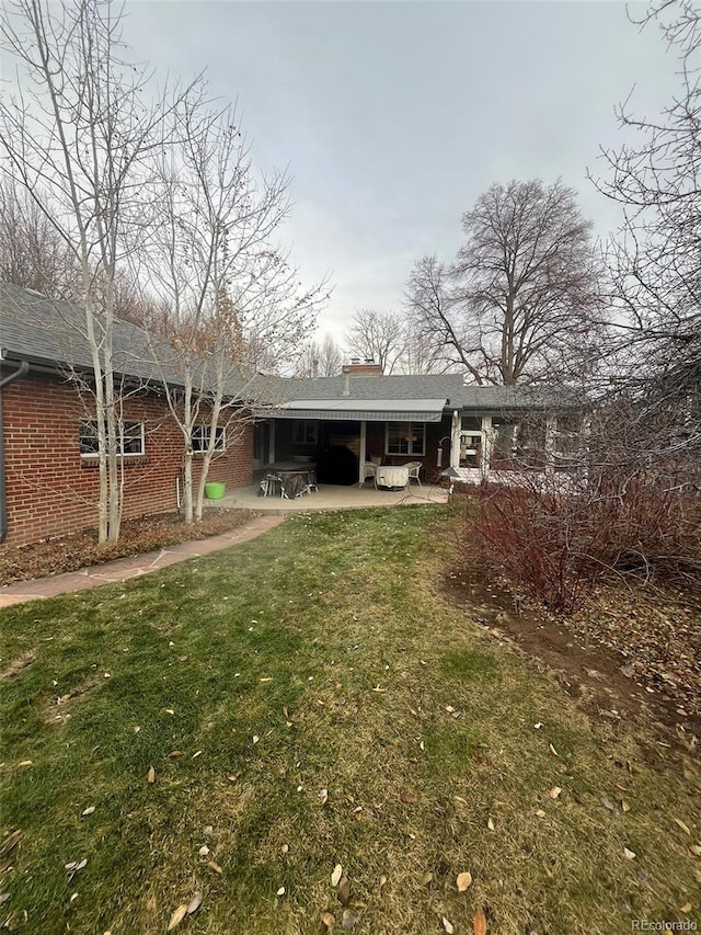 rear view of house with a patio and a lawn