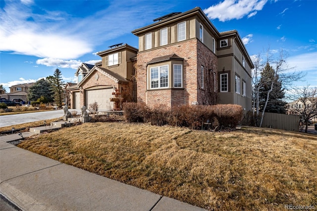 view of front of home featuring brick siding, fence, concrete driveway, stucco siding, and a front yard