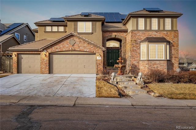 view of front facade with a garage, roof mounted solar panels, driveway, and stucco siding