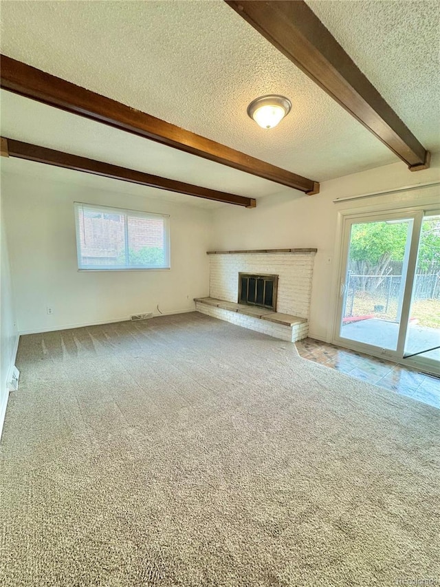 13024 E Alaska Pl, Aurora, CO 80012 - unfurnished living room with a textured ceiling, beamed ceiling, a fireplace, and carpet flooring