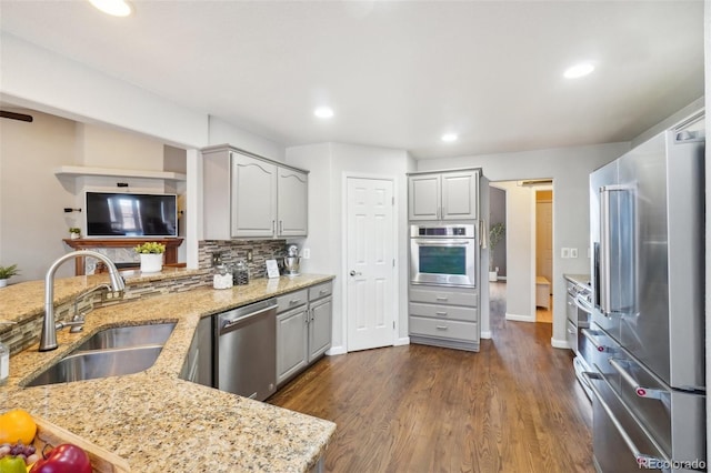 kitchen with light stone counters, sink, gray cabinets, and stainless steel appliances