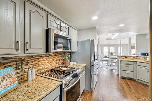 kitchen featuring dark wood-type flooring, appliances with stainless steel finishes, light stone countertops, and gray cabinetry