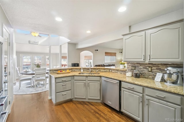 kitchen featuring sink, light stone countertops, kitchen peninsula, and dishwasher