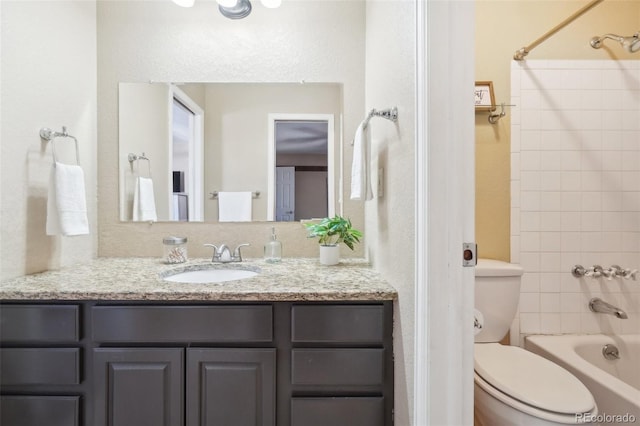 full bathroom featuring tiled shower / bath, vanity, and toilet