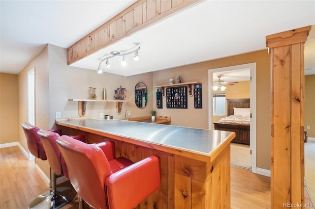 kitchen featuring ceiling fan, kitchen peninsula, a breakfast bar area, and light wood-type flooring