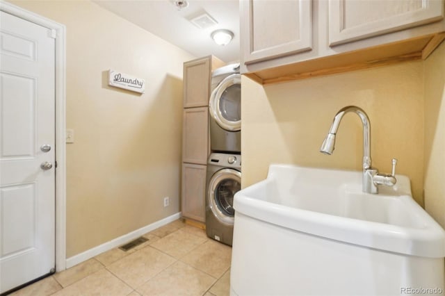 washroom featuring stacked washer / drying machine, sink, cabinets, and light tile patterned floors