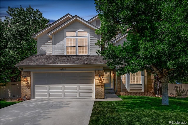 traditional-style house featuring brick siding, concrete driveway, an attached garage, fence, and a front yard