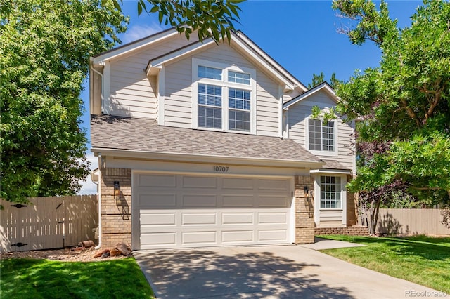 traditional-style home with driveway, an attached garage, fence, and brick siding