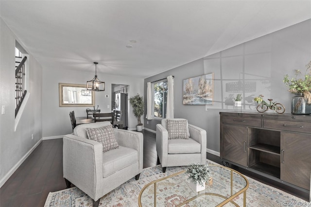 living area with dark wood-style floors, baseboards, and an inviting chandelier