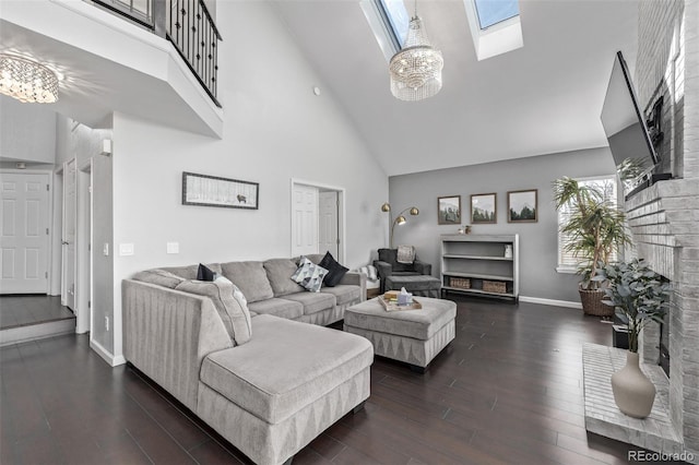 living room with a skylight, a fireplace, dark wood finished floors, an inviting chandelier, and high vaulted ceiling