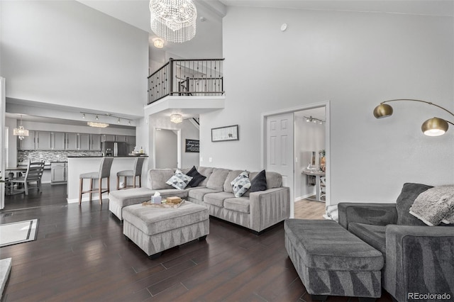 living area with dark wood-style floors, a notable chandelier, and a high ceiling