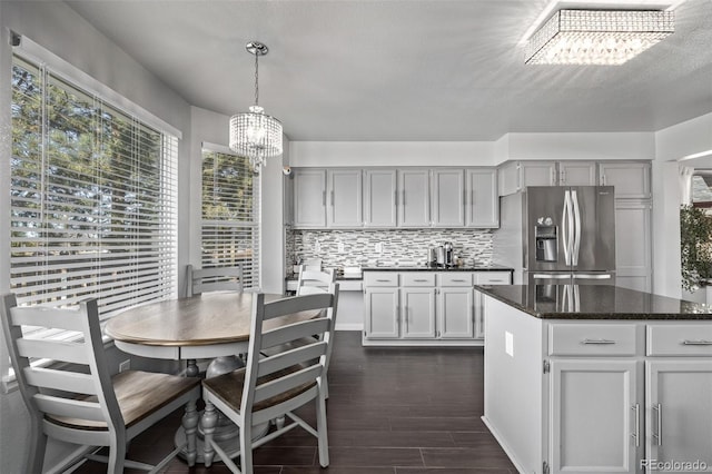 kitchen with a notable chandelier, gray cabinets, stainless steel fridge with ice dispenser, dark wood-style floors, and tasteful backsplash