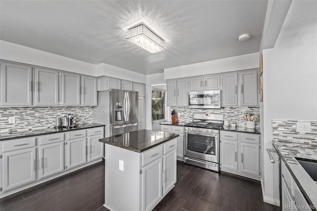 kitchen with a kitchen island, dark stone countertops, dark wood-style flooring, stainless steel appliances, and backsplash