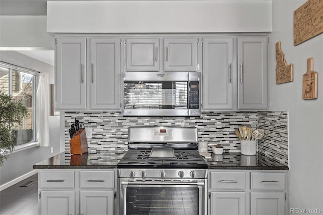 kitchen featuring tasteful backsplash, visible vents, appliances with stainless steel finishes, dark stone counters, and baseboards