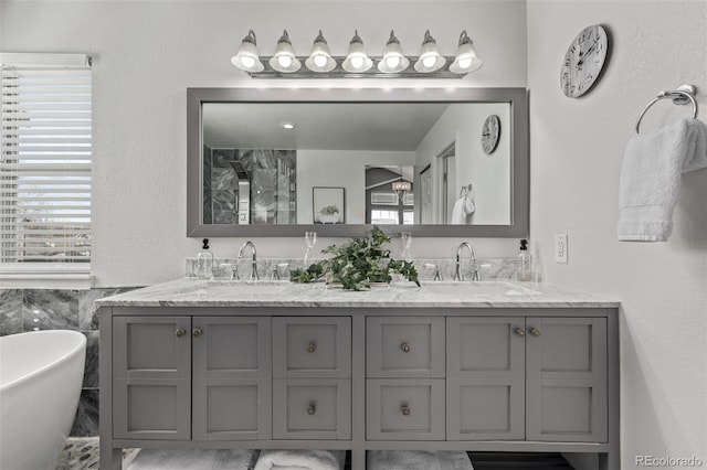 bathroom with a freestanding bath, double vanity, plenty of natural light, and a sink