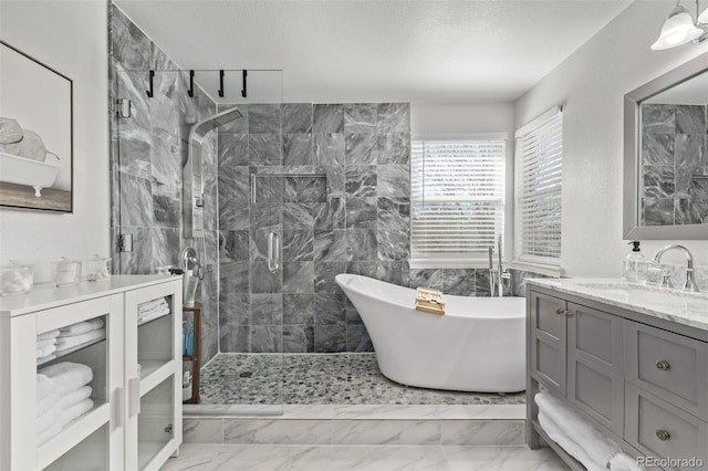 full bathroom featuring marble finish floor, a soaking tub, a shower stall, vanity, and a textured ceiling