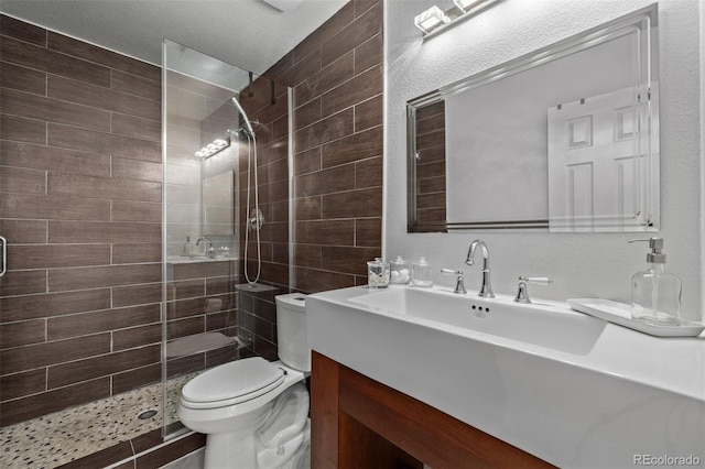 bathroom featuring toilet, a tile shower, and vanity