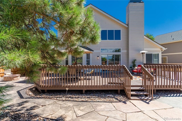 back of property with a chimney and a wooden deck