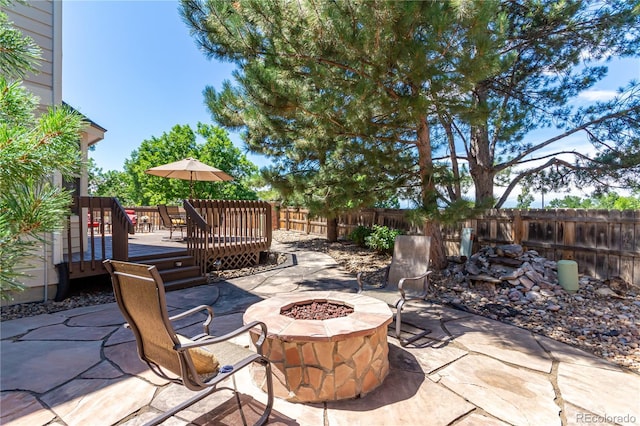 view of patio / terrace with a fire pit, fence, and a wooden deck