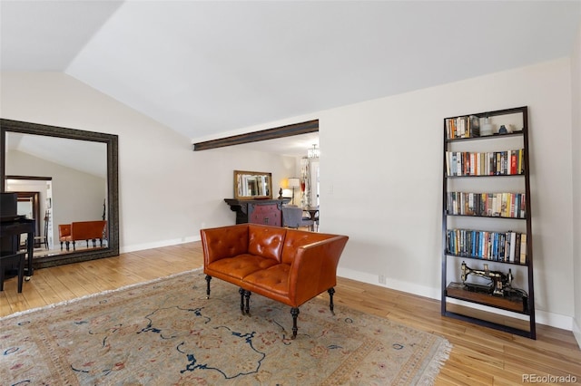 living area with a notable chandelier, vaulted ceiling, and light hardwood / wood-style flooring