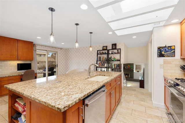 kitchen with light stone countertops, a kitchen island with sink, a skylight, appliances with stainless steel finishes, and sink