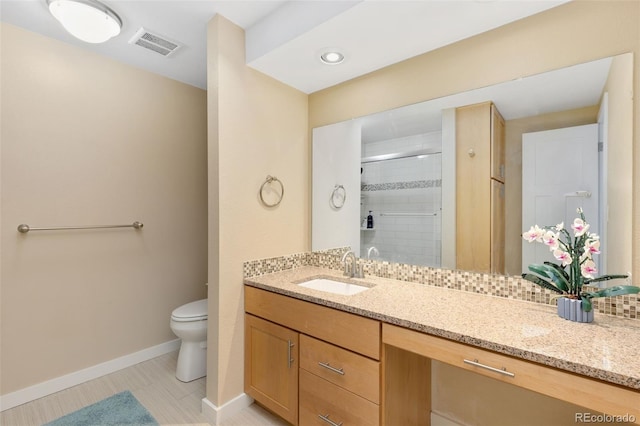 bathroom featuring toilet, vanity, tasteful backsplash, and walk in shower