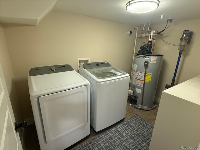 laundry area with dark tile patterned floors, laundry area, washer and clothes dryer, and gas water heater