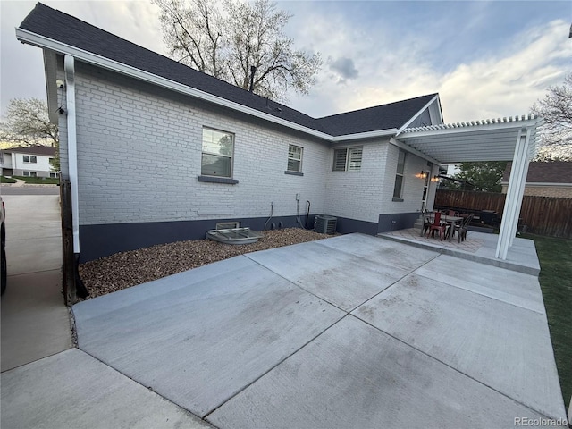 rear view of house featuring a patio area, brick siding, fence, cooling unit, and outdoor dining space