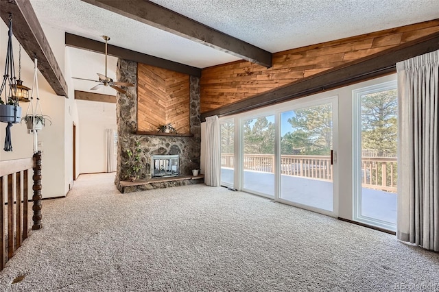 unfurnished living room featuring carpet flooring, a stone fireplace, ceiling fan, and a healthy amount of sunlight