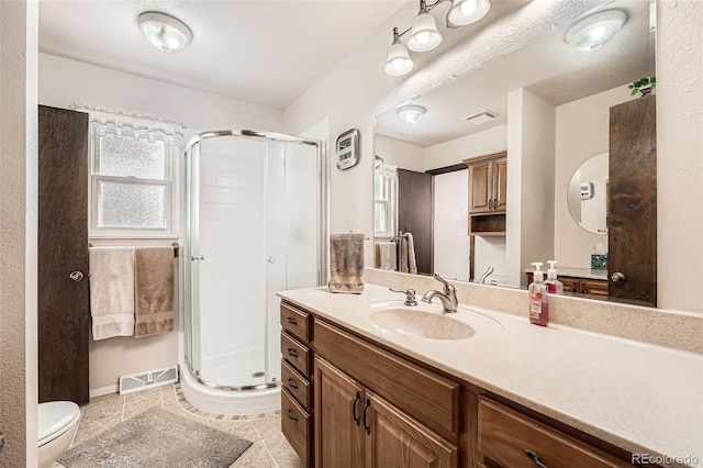 bathroom featuring tile patterned flooring, vanity, toilet, and walk in shower